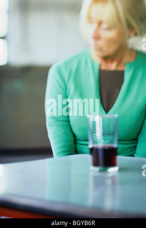 Frau sitzend am Tisch mit Getränken Stockfoto