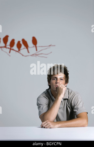 Junger Mann sitzen, stützte sich auf Ellbogen, Porträt Stockfoto