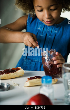 Mädchen Vorbereitung Snack von Brot und Marmelade Stockfoto