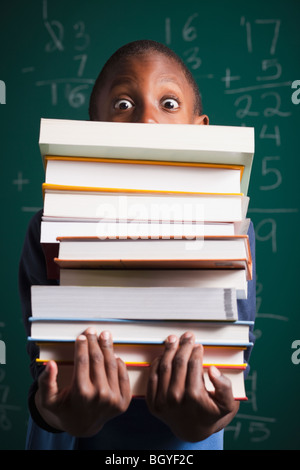 Boy Holding Stapel Bücher Stockfoto