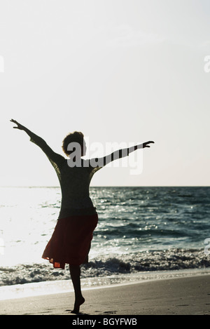 Frau balancieren auf einem Bein am Strand, mit Blick auf See, silhouette Stockfoto