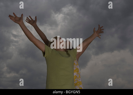 Jungen und Mädchen mit erhobenen Armen zurück Köpfen bewölktem Himmel blickte Stockfoto