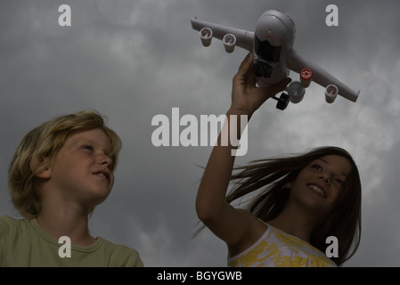 Mädchen spielen mit Spielzeugflugzeug, jüngerer Bruder ansehen Stockfoto