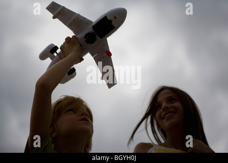 Jungen spielen mit Spielzeugflugzeug, ältere Schwester beobachten, Lächeln Stockfoto