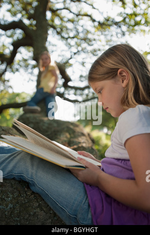 Mädchen-Lesebuch in Baum Stockfoto