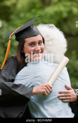 Absolvent umarmt Seniorin Stockfoto