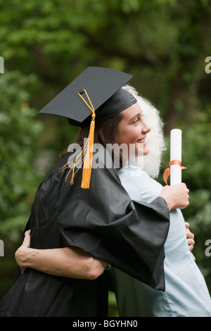 Absolvent umarmt Seniorin Stockfoto