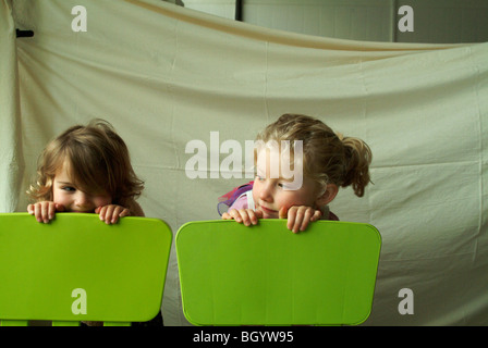 Zwei kleine Mädchen mit Blick auf die Rückseite des passenden grünen Stühle. Stockfoto