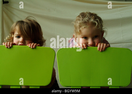 Zwei kleine Mädchen mit Blick auf die Rückseite des passenden grünen Stühle. Stockfoto