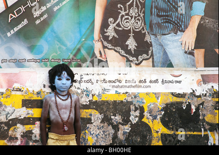 Indischer Junge, Gesicht gemalt als Hindu Gott Shiva vor einem Bollywood Film Poster. Andhra Pradesh, Indien Stockfoto