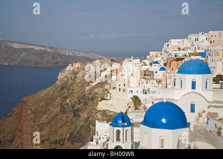Oia-Stadt auf einer Klippe mit weißen Kirchen mit blauen Kuppeln und Blick auf Santorinis Caldera und das Lagunenwasser im Mittelmeer Stockfoto