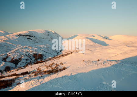 Rot Geröllhalden und Kirkstone Pass abgedeckt im Schnee bei Sonnenuntergang von Wansfell im Lake District, UK. Stockfoto