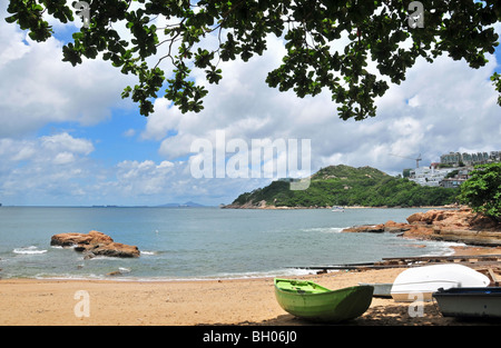 Ansicht von Stanley Bay, mit überhängenden Baum, kleine Boote am Strand, blauer Himmel und weiße Wolken, Stanley, Hong Kong, China Stockfoto