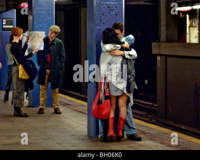 Gleichgültig gegenüber ihrer Umgebung, ein junges Paar küssen in New York Citys 2nd Avenue u-Bahnstation. Stockfoto