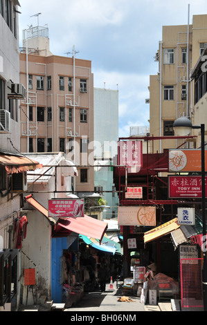Freiem Himmel Geschäfte, beschattet von Jalousien unten Wohnblocks an den Seiten einer Straße in Stanley Market, Stanley, Hong Kong, China Stockfoto