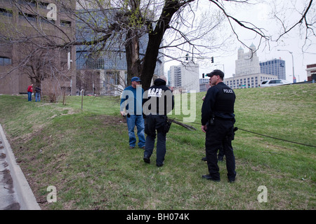 Polizisten suchen den Boden nach Drogen nach der Festnahme von Verdächtigen, die angeblich Drogen warf und lief. Stockfoto