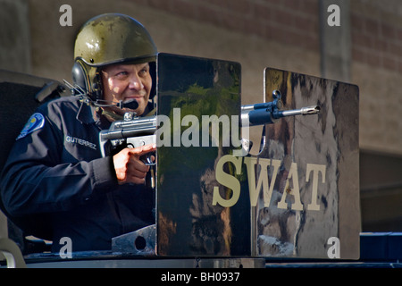 Trägt einen Stahlhelm, Ziel ist ein Hispanic SWAT (spezielle Waffen und Taktiken) Team-Polizist einen Maschinengewehr Hinweis gepanzerte Schild Stockfoto
