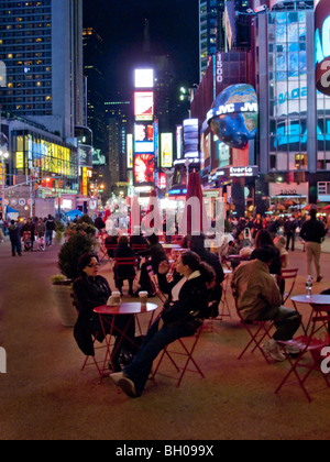 Gartentische und Stühle fördern Menschen in New York City Times Square mit seinen hellen outdoor Schilder zu entspannen. Stockfoto