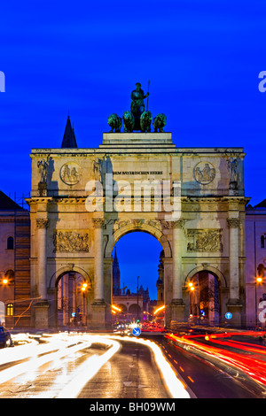 Das Siegestor (Siegestor) mit Datenverkehr um ihn herum in der Abenddämmerung im Stadtteil Schwabing in der Stadt München (München), B Stockfoto