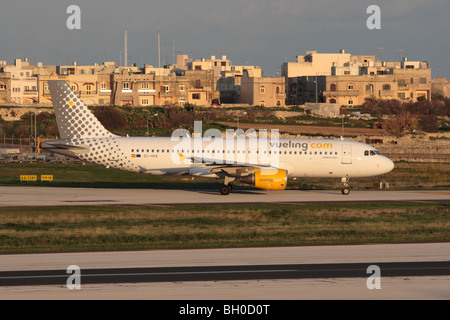 Günstige Flugreisen und Massentourismus. Vueling Airbus A320 Rollen für die Abfahrt aus Malta bei Sonnenuntergang Stockfoto