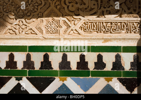 Palast von Alhambra, Granada, Andalusien, Spanien. Detail der kunstvoll geschnitzten Wand und Fliesen. Stockfoto