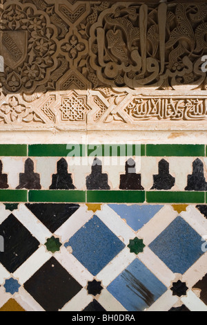 Palast von Alhambra, Granada, Andalusien, Spanien. Detail der kunstvoll geschnitzten Wand und Fliesen. Stockfoto