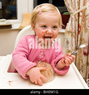 Platz in der Nähe bis Porträt eines Mädchens in einem Durcheinander in ihrem Hochstuhl Schokoladeneis zu essen bekommen. Stockfoto