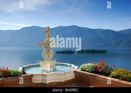 Lago Maggiore mit Insel Brissago, Isole di Brissago und Monte Gambarogno mit Brunnen und Blumen im Vordergrund, Ronco Stockfoto
