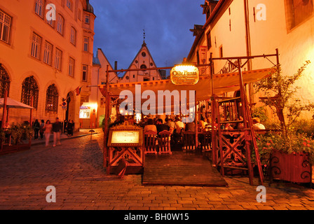 Tische im Freien das Olde Hansa Restaurant mit mittelalterlichen Gerichten am Abend, Tallinn, Estland Stockfoto