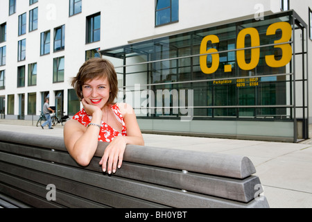 Junge Frau sitzt auf einer Bank, Köln, Nordrhein-Westfalen, Deutschland Stockfoto