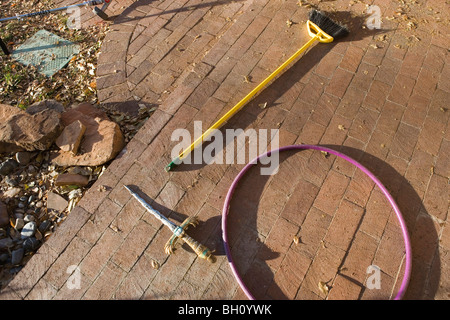 Objekte links auf Veranda von Kindern, Besen, Spielzeug Schwert und hoolahoop Stockfoto
