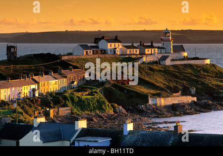 Häuser und Leuchtturm an der Küste im Licht der Abendsonne, Roche Point, County Cork, Irland, Europa Stockfoto