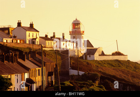 Häuser und Leuchtturm an der Küste im Licht der Abendsonne, Roche Point, County Cork, Irland, Europa Stockfoto
