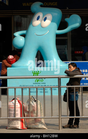 Ein Passagier wartet außerhalb der Wartehalle und Backdropped von einer Skulptur des "Hai Bao", das Maskottchen der Expo 2010 in Shanghai Stockfoto