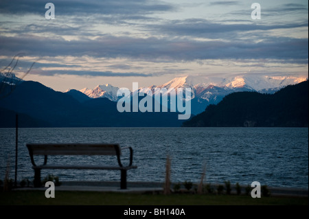 Eine Bank vor Harrison Hot Springs Resort &amp; Spa. Harrison Lake und der kanadischen Kaskade Berge im Hintergrund. Stockfoto