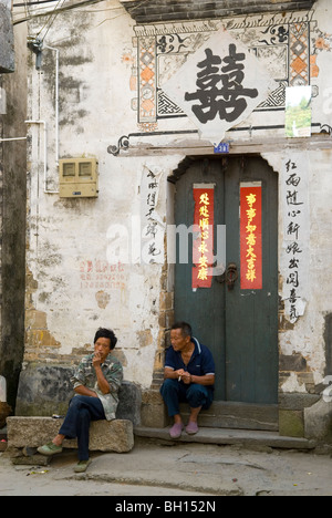Zwei Männer sitzen vor ein altes Haus von Huizhou-Stil in großen Likeng. Provinz Jiangxi. China