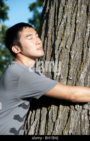 Junger Mann umarmt Baum, Assiniboine Park, Winnipeg, Manitoba, Kanada Stockfoto