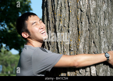 Junger Mann umarmt Baum, Assiniboine Park, Winnipeg, Manitoba, Kanada Stockfoto