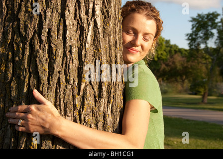 Frau in ihrem 40er Umarmungen Baum in Assiniboine Park, Winnipeg, Manitoba, Kanada Stockfoto