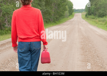 Frau mit Rücken zur Kamera auf Landstraße mit Kanister, Manitoba, Kanada Stockfoto