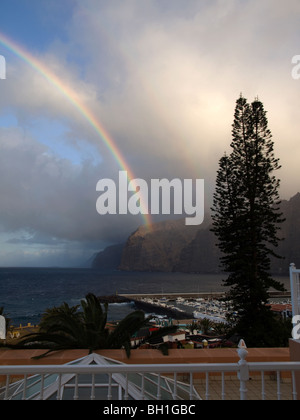 Eine Dusche Regen bringt einen Regenbogen zu den riesigen Klippen im Resort von Los Gigantes-Teneriffa Stockfoto