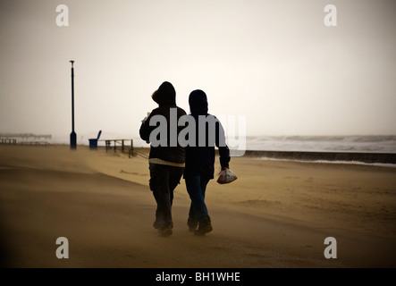 Menschen in extremen Wetterbedingungen. Sand ist am Strand und entlang der Strandpromenade von starkem Wind geblasen. Bournemouth. Dorset. VEREINIGTES KÖNIGREICH. Winter. Stockfoto