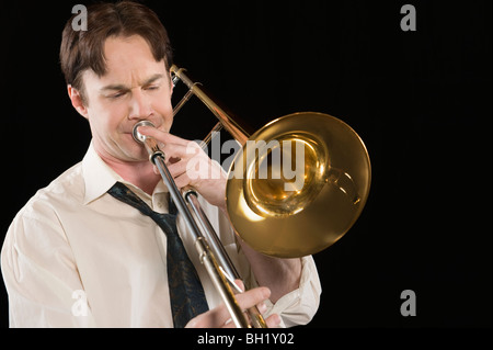 Mid-Adult Mann mit offenen Kragen Hemd spielt die Posaune Stockfoto