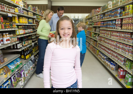 Mädchen steht Blick in die Kamera, mit der Familie im Supermarkt einkaufen Stockfoto