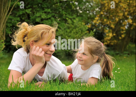 Junge Mutter und Tochter, die Verlegung auf dem Rasen Stockfoto