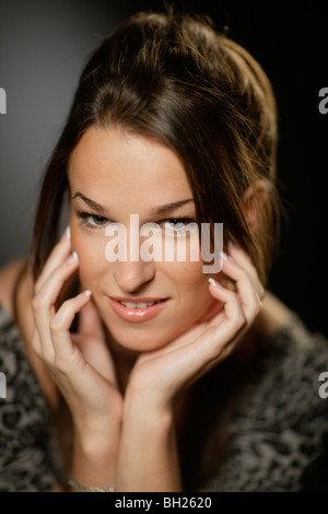 Junge dunkelhaarige Frau, die ihren Kopf in ihre Hände ruhen Stockfoto