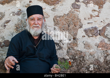 Traurig ältere griechisch-orthodoxen Priester in Roben und Bart mit Rohrstock Stockfoto