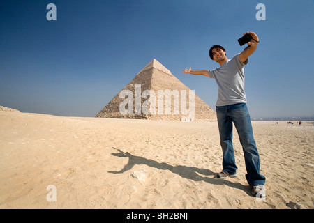 Mann, der ein Bild von sich mit Pyramide im Hintergrund Stockfoto