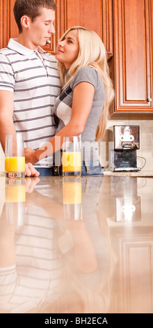 Junges Paar Lächeln einander mit Gläser Orangensaft auf Zähler. Vertikale erschossen. Stockfoto