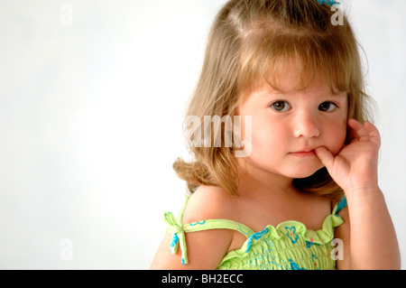 Young-hispanischen Mädchen spielt mit ihrem Spielzeug Roller und sieht mehr als ein bisschen schüchtern, als sie in die Linse ihre Daumenlutschen sieht. Stockfoto